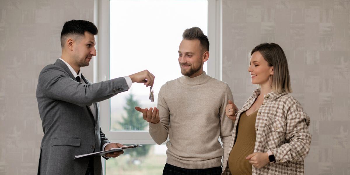 A real estate agent hands house keys to a couple in a new home